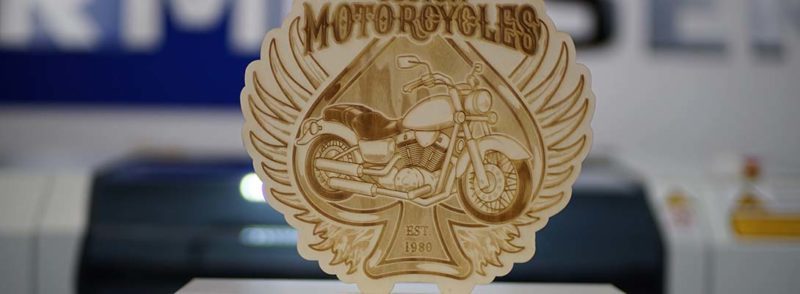 Ein eingraviertes Holzschild mit der Abbildung eines Motorrads.